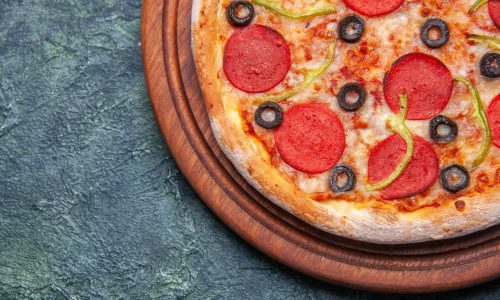 close-up-view-delicious-pizza-wooden-cutting-board-left-side-dark-blue-surface-with-free-space